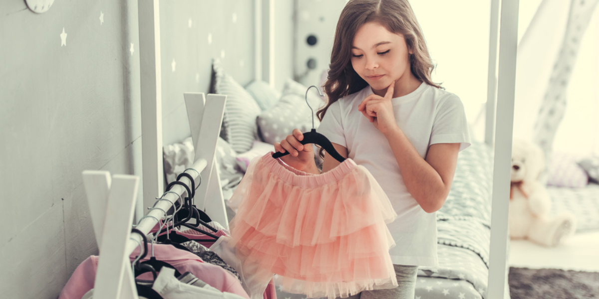 Κορίτσι που κατηγοριοποιεί ρούχα στην παιδική ντουλάπα